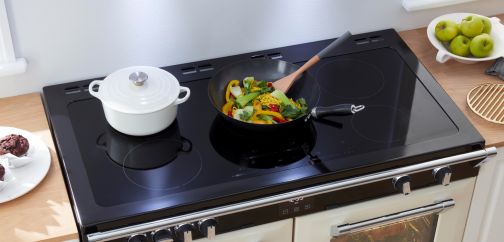 A range cooker with an induction cooktop being used with a frying pan and saucepan